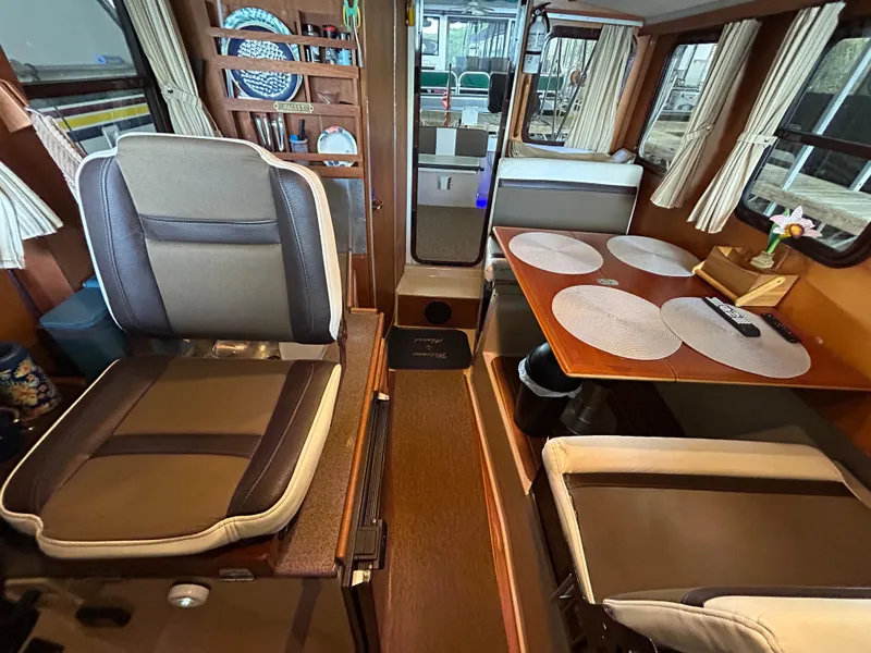 Slide: The Image of 2016 Ranger Tugs R-25SC interior with seating, dining area, and nautical decor. - 25