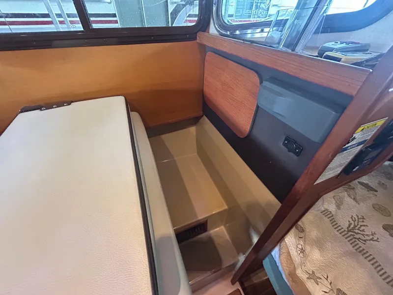Slide: The Image of 2016 Ranger Tugs R-25SC interior seating area with wood accents and window view. - 37