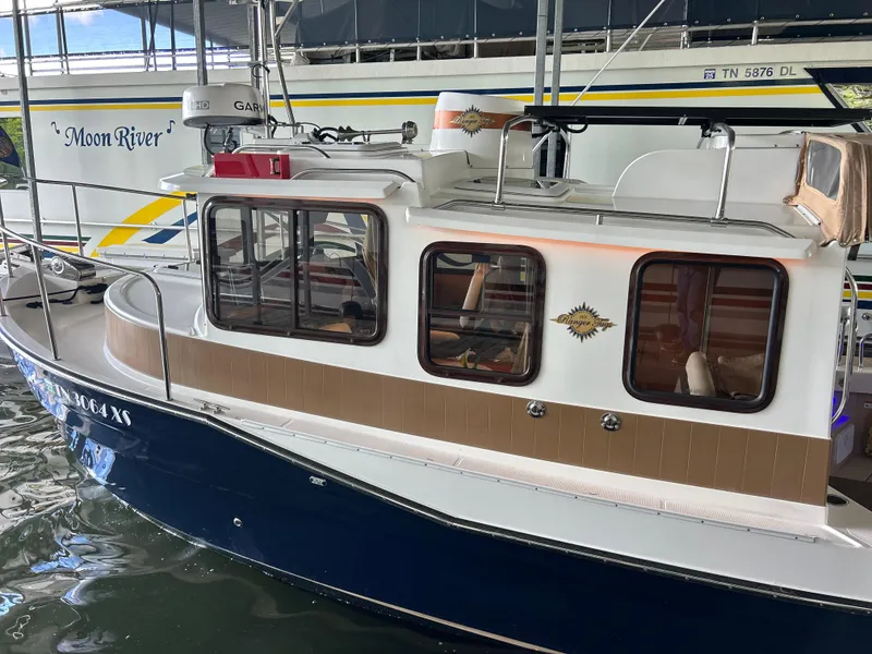 Slide: The Image of 2016 Ranger Tugs R-25SC boat docked, featuring a blue and white exterior with cabin windows. - 4