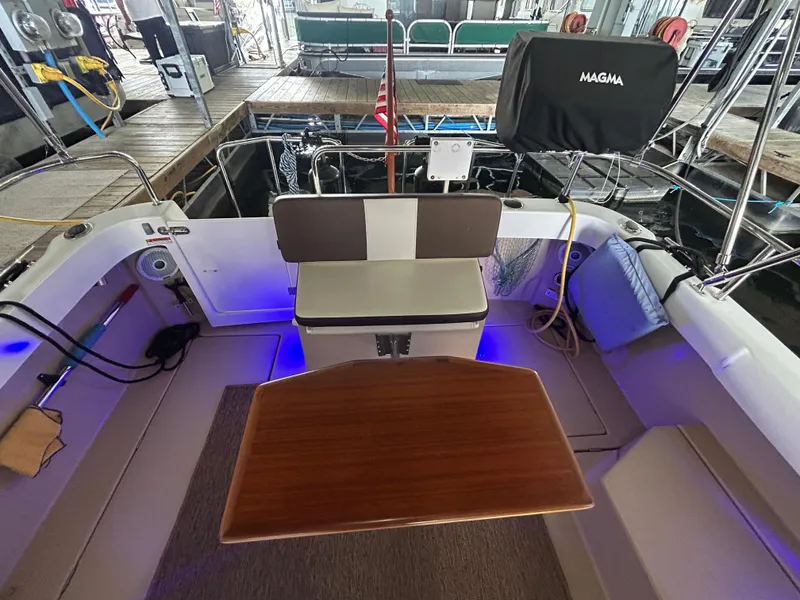 Slide: The Image of 2016 Ranger Tugs R-25SC boat interior with seating and table, docked in a marina. - 43