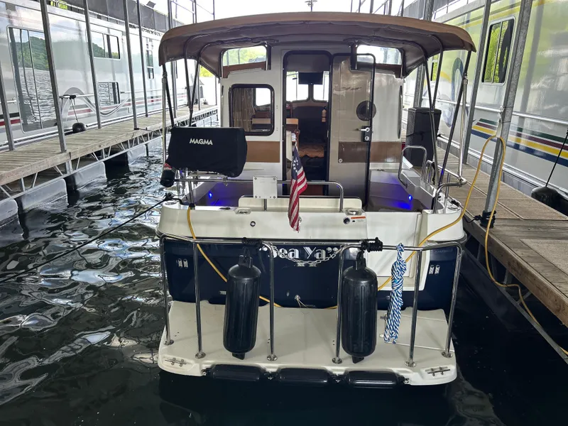 Slide: The Image of 2016 Ranger Tugs R-25SC docked, rear view with American flag and fenders. - 8