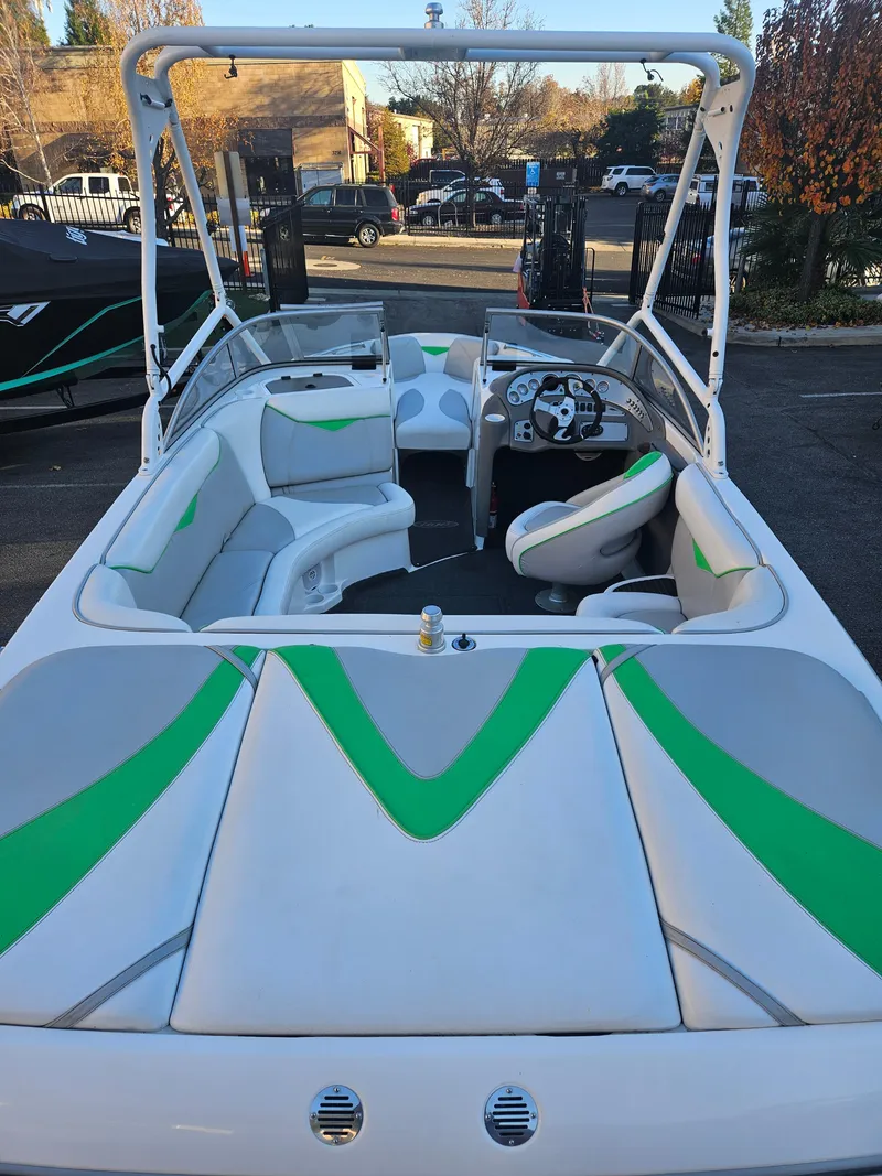 Slide: The Image of 2005 Tigé 22V boat interior with green and gray seating, parked outdoors. - 2