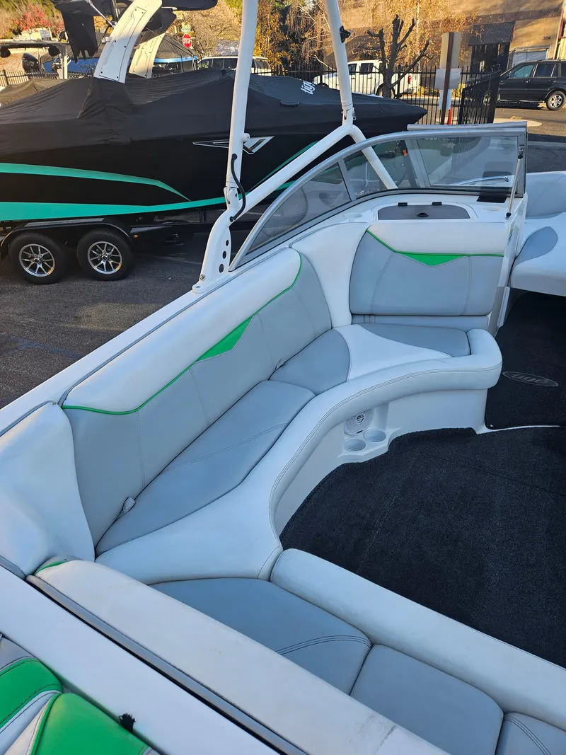Slide: The Image of 2005 Tigé 22V boat interior with white and green seating, parked outdoors. - 6