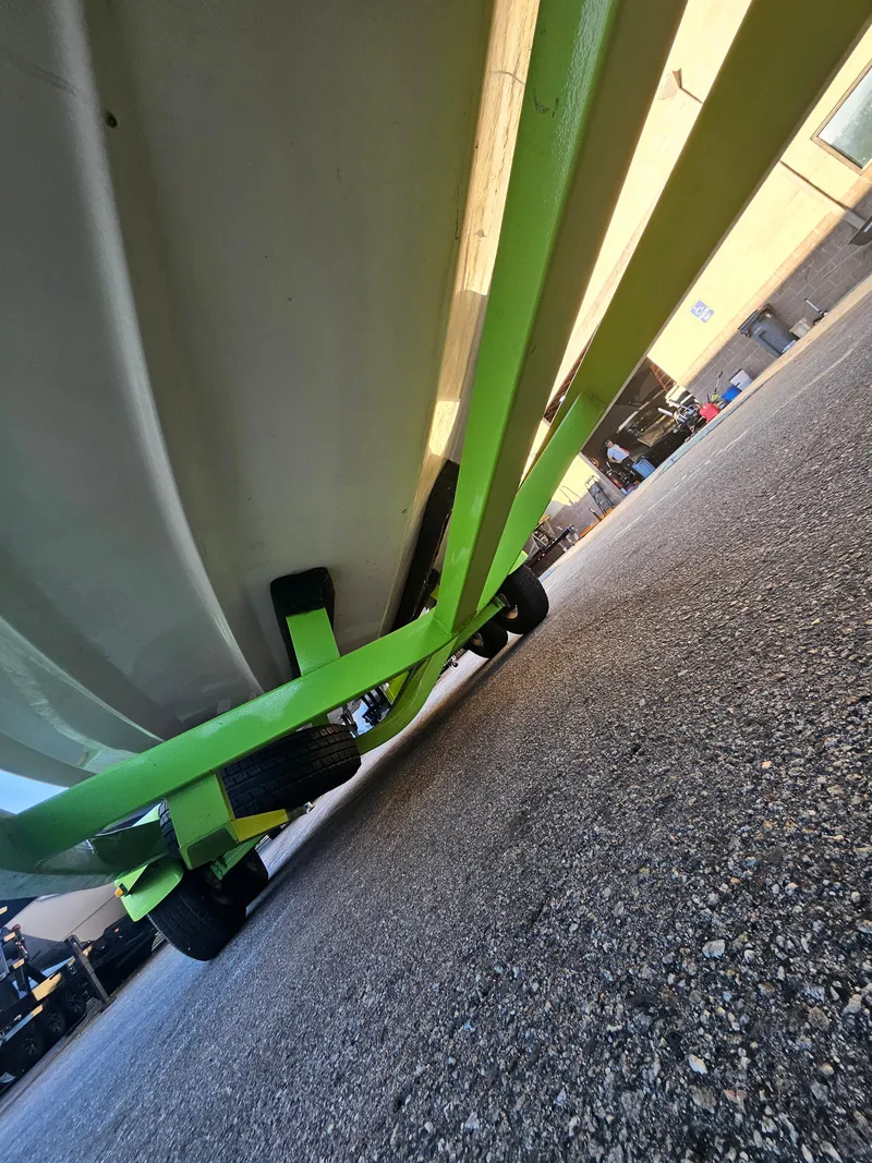 Slide: The Image of Underneath view of a 2005 Tigé 22V boat on a bright green trailer. - 8