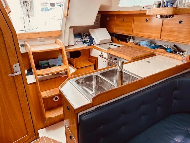 Slide: The Image of Cozy 2003 Catalina 36 MkII yacht interior with wooden cabinetry and compact kitchen area. - 22