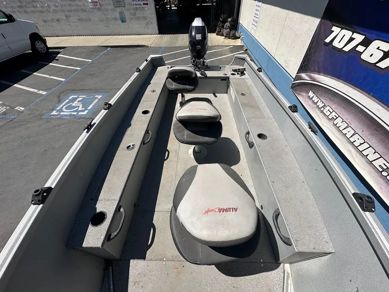Slide: The Image of 2018 Alumacraft Yukon 165 boat interior with seating and motor, parked in a lot. - 14