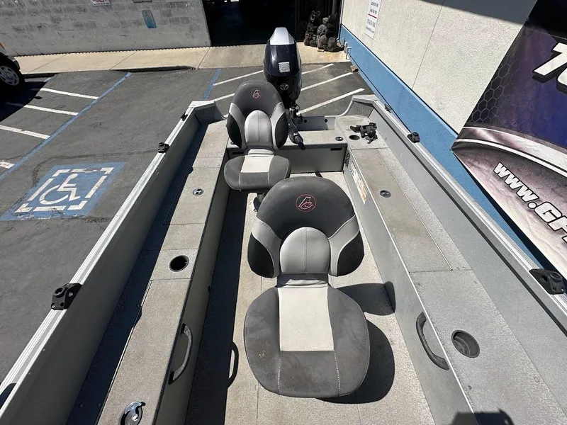 Slide: The Image of 2018 Alumacraft Yukon 165 boat interior with seating and motor, parked in a lot. - 16