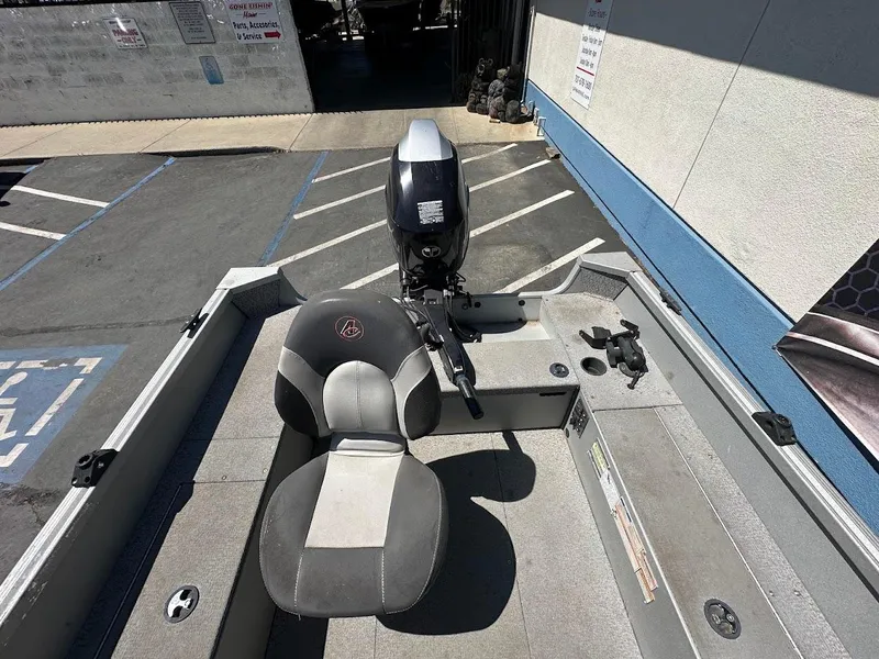 Slide: The Image of 2018 Alumacraft Yukon 165 boat interior with seating and motor in a parking area. - 17