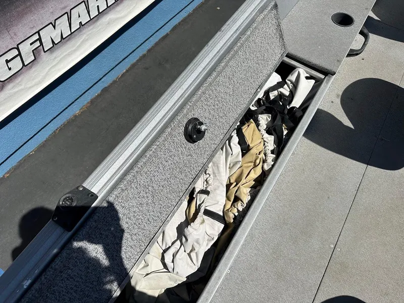 Slide: The Image of Storage compartment in 2018 Alumacraft Yukon 165 boat, partially open with gear inside. - 19