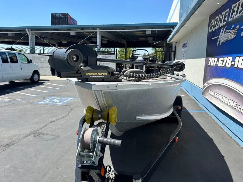 Slide: The Image of 2018 Alumacraft Yukon 165 boat on trailer, parked outside a marine shop. - 3