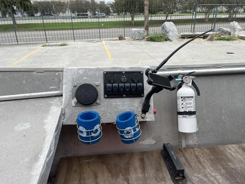 Slide: The Image of Control panel with switches, cup holders, and fire extinguisher on a Custom 17 boat, 2006 model. - 12