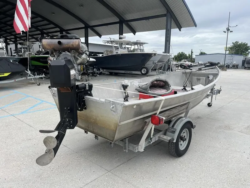 Slide: The Image of Custom 2006 model 17 boat with outboard motor on trailer, parked outdoors. - 3