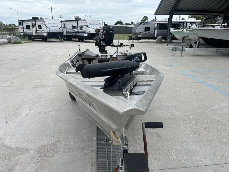 Slide: The Image of Aluminum fishing boat with motor, parked near RVs and trailers, overcast sky. - 9