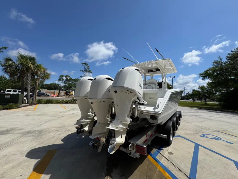 Slide: The Image of 2018 Jupiter 34 HFS boat with triple outboard engines on a trailer under a clear blue sky. - 13