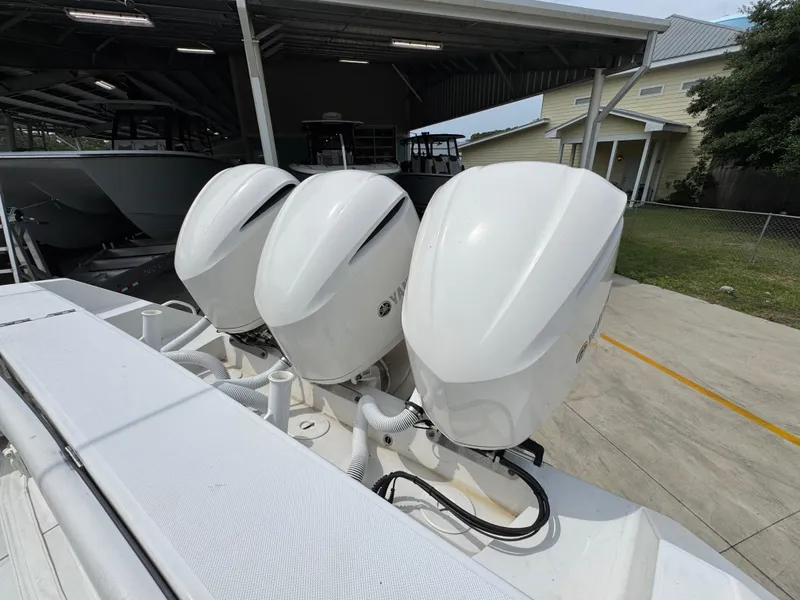Slide: The Image of Triple outboard engines on a 2018 Jupiter 34 HFS boat, parked under a shelter. - 37