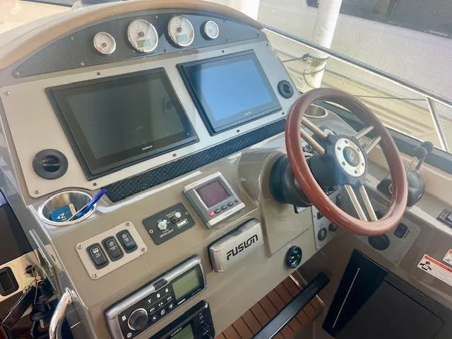 Slide: The Image of Control panel of a 2011 Regal 46 Sport Coupe with dual screens and wooden steering wheel. - 16