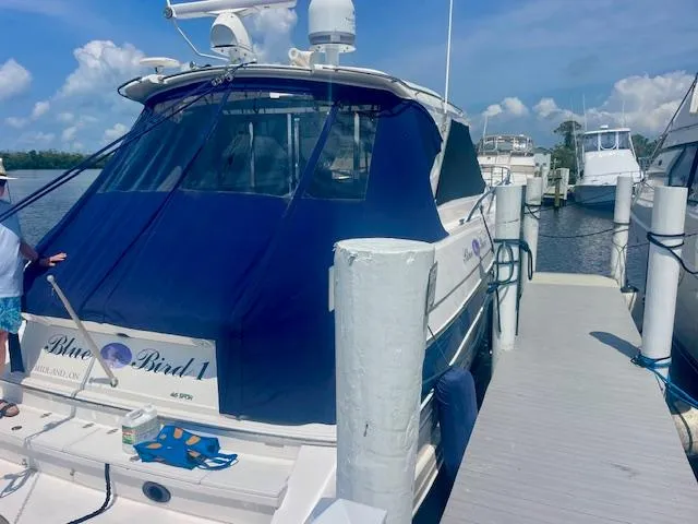 Slide: The Image of 2011 Regal 46 Sport Coupe docked, covered in blue tarp, sunny day. - 2