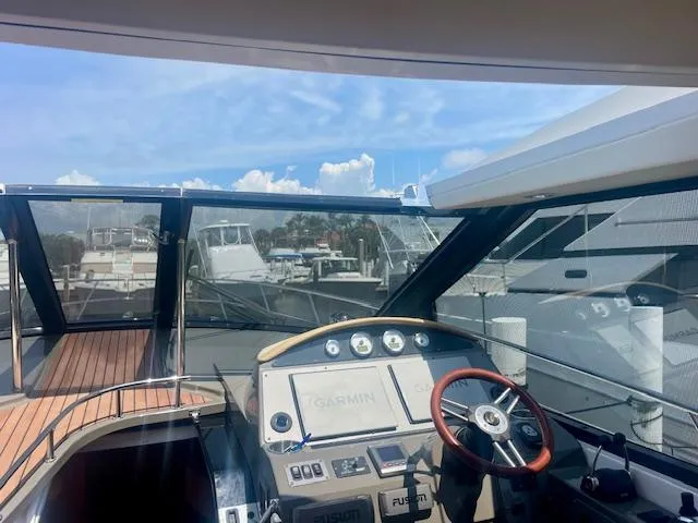 Slide: The Image of 2011 Regal 46 Sport Coupe yacht helm with Garmin navigation, docked under a clear sky. - 31