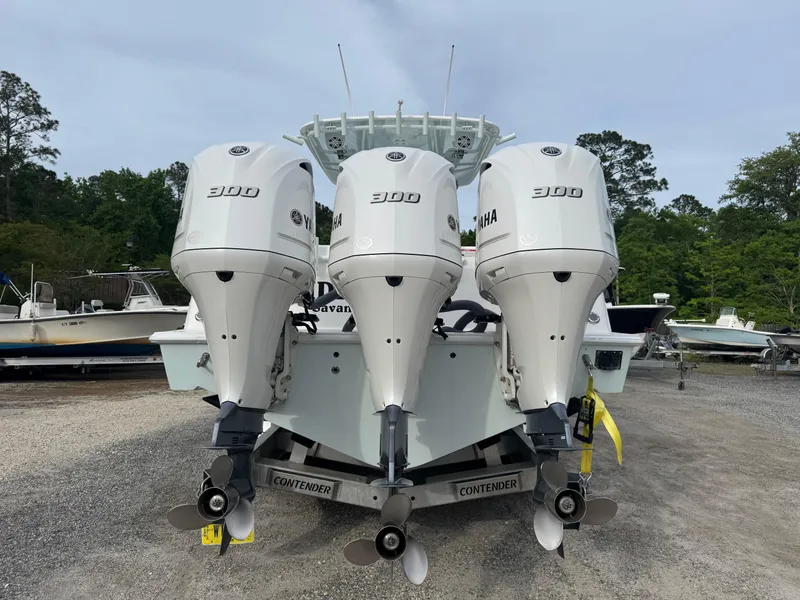 Slide: The Image of 2019 Contender 35 ST boat with triple Yamaha 300 engines, parked on gravel. - 35