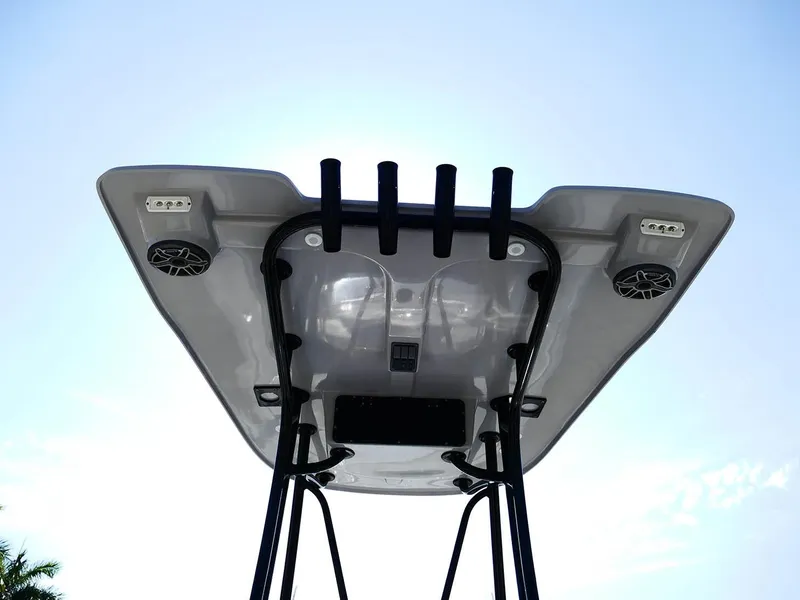 Slide: The Image of 2022 Contender 25 Bay boat T-top with rod holders and speakers against blue sky. - 10