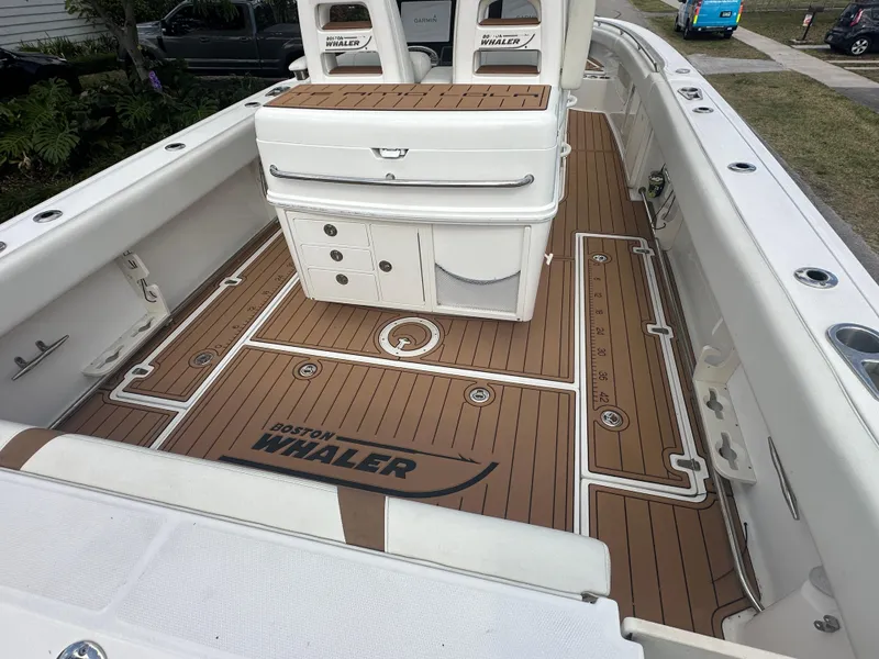Slide: The Image of 2013 Boston Whaler 320 Outrage boat interior with teak-style flooring and storage compartments. - 10