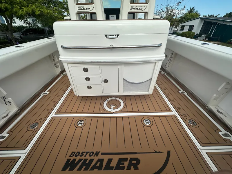 Slide: The Image of 2013 Boston Whaler 320 Outrage boat interior with storage compartments and teak-style flooring. - 13