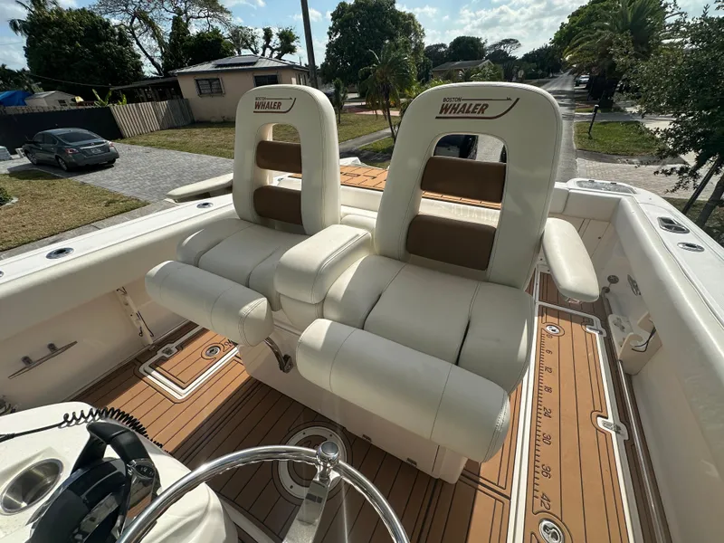 Slide: The Image of 2013 Boston Whaler 320 Outrage boat interior with dual white captain's chairs and teak flooring. - 16