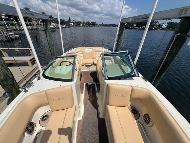 Slide: The Image of 2013 Chris-Craft Launch 22 boat interior with tan seating, docked by a scenic waterfront. - 10
