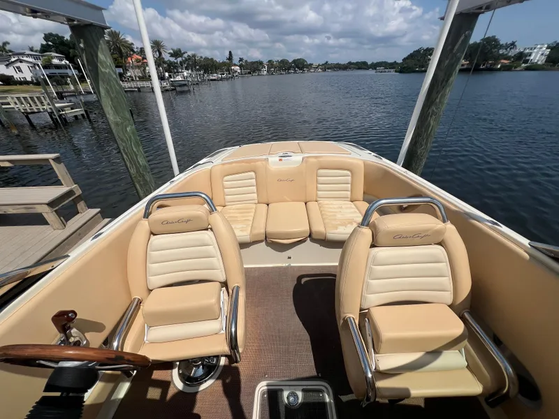 Slide: The Image of 2013 Chris-Craft Launch 22 boat interior with beige seating, docked by a scenic waterfront. - 11