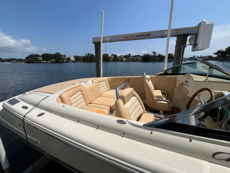 Slide: The Image of 2013 Chris-Craft Launch 22 boat with beige interior, docked by a scenic waterfront. - 12