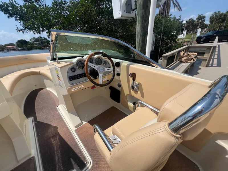 Slide: The Image of 2013 Chris-Craft Launch 22 boat interior with beige seating and wooden steering wheel. - 13