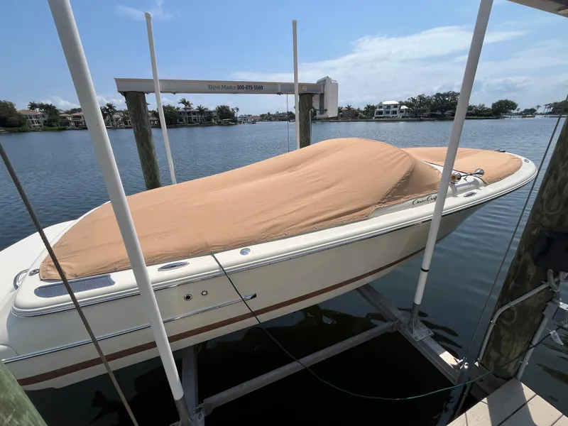 Slide: The Image of 2013 Chris-Craft Launch 22 boat covered and docked on a lift by the water. - 20