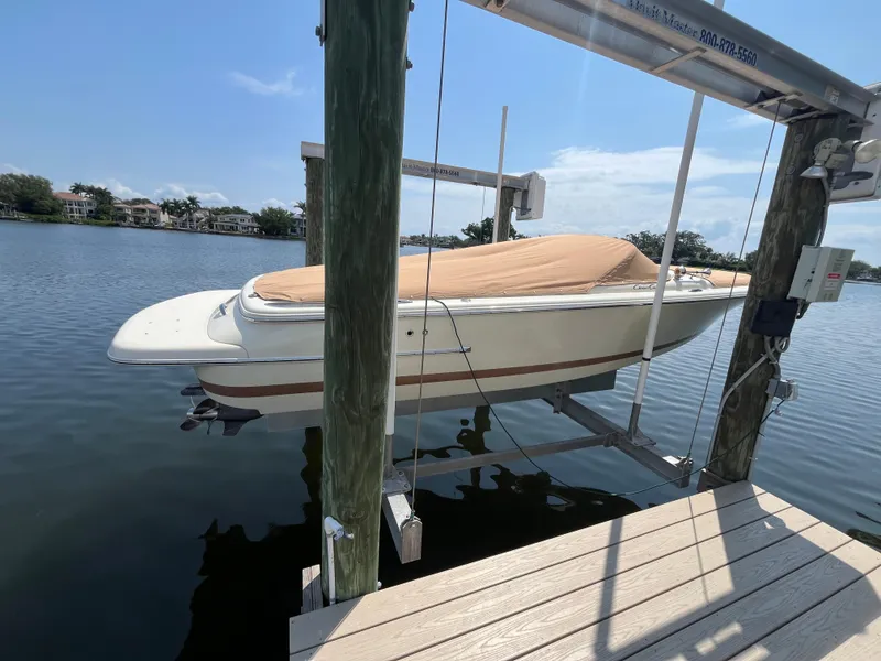 Slide: The Image of 2013 Chris-Craft Launch 22 boat on lift, covered, docked by calm waters. - 21