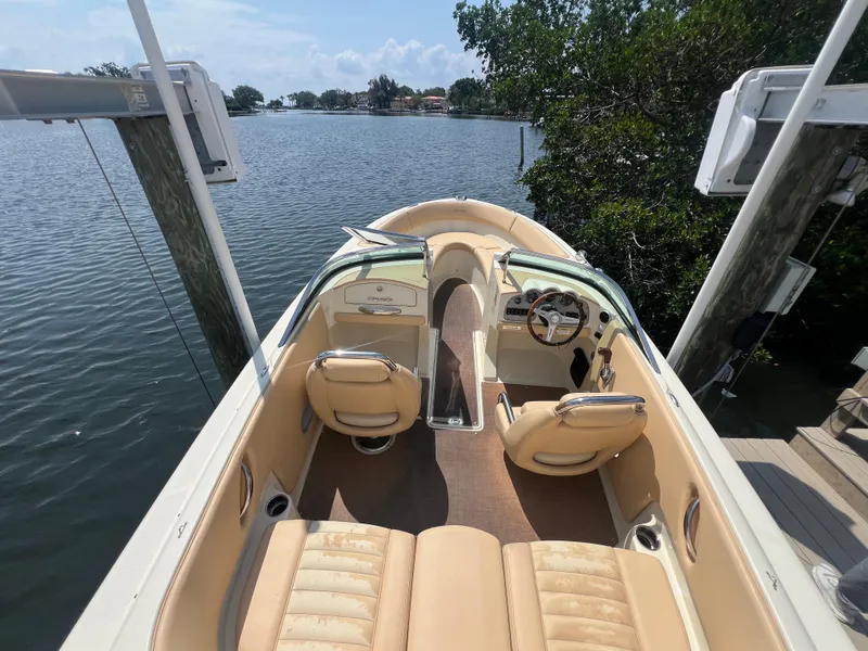 Slide: The Image of 2013 Chris-Craft Launch 22 boat with tan interior, docked by a serene waterfront. - 3