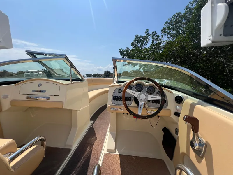 Slide: The Image of 2013 Chris-Craft Launch 22 boat interior with steering wheel, dashboard, and seating under clear sky. - 7