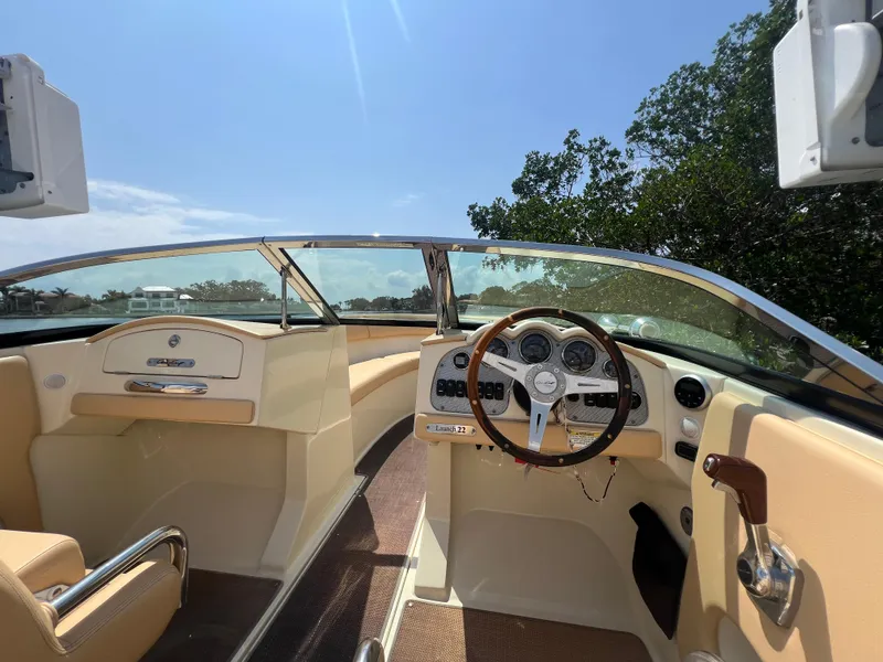Slide: The Image of 2013 Chris-Craft Launch 22 boat interior with steering wheel and dashboard under clear sky. - 8
