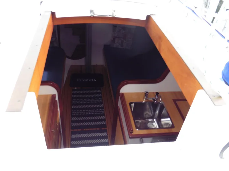Slide: The Image of Interior view of 2011 Cape George Cutter sailboat, featuring a compact kitchen and seating area. - 22