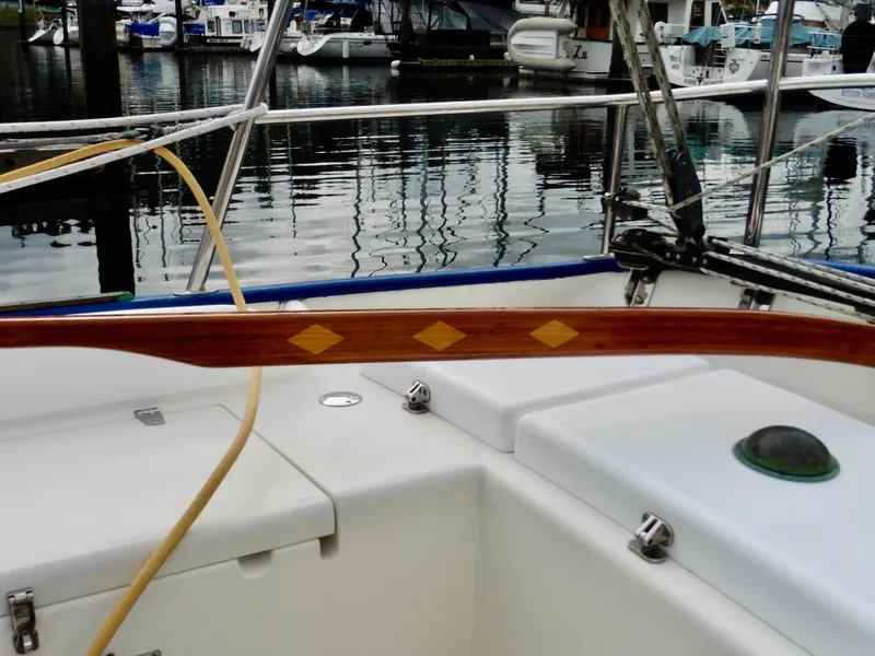 Slide: The Image of Cape George Cutter 2011 sailboat cockpit with wooden tiller and marina background. - 29