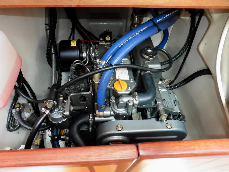 Slide: The Image of Engine compartment of a 2011 Cape George Cutter sailboat, featuring blue hoses and mechanical components. - 38