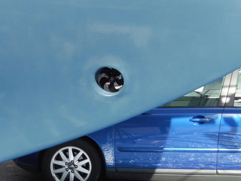 Slide: The Image of Blue Cape George Cutter 2011 hull with visible propeller, parked beside a blue car. - 4