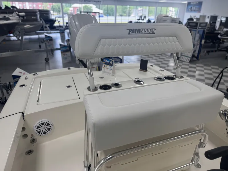 Slide: The Image of 2025 Pathfinder 2300 HPS boat interior with white seating and control panel in showroom. - 5