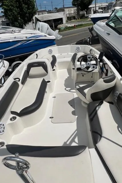 Slide: The Image of 2019 Stingray 182 SC boat interior with seating and steering wheel, docked outdoors. - 6