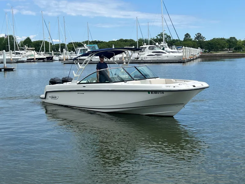 Slide: The Image of 2016 Boston Whaler 270 Vantage boat cruising in a marina with sailboats in the background. - 2