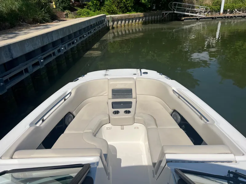 Slide: The Image of 2016 Boston Whaler 270 Vantage boat interior with seating, docked by calm water. - 9