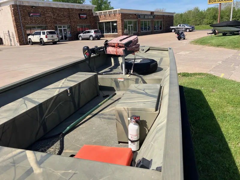 Slide: The Image of 2006 Tracker GRIZZLY 1648 AWL boat parked near a store, featuring outdoor equipment. - 8