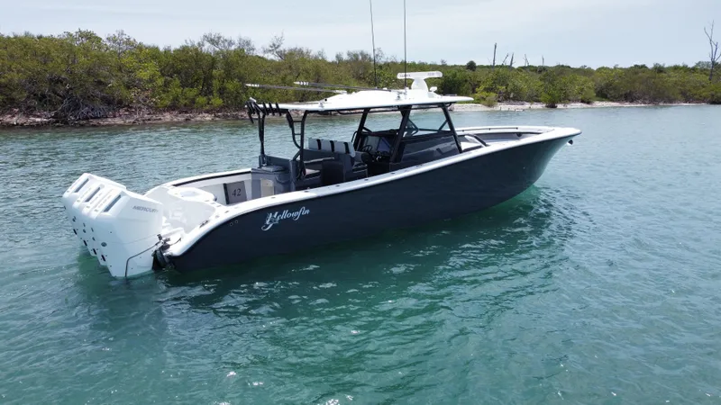 Slide: The Image of 2023 Yellowfin 42 boat on calm water near a lush shoreline. - 10