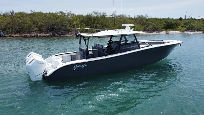 Slide: The Image of 2023 Yellowfin 42 boat on water near lush shoreline. - 11