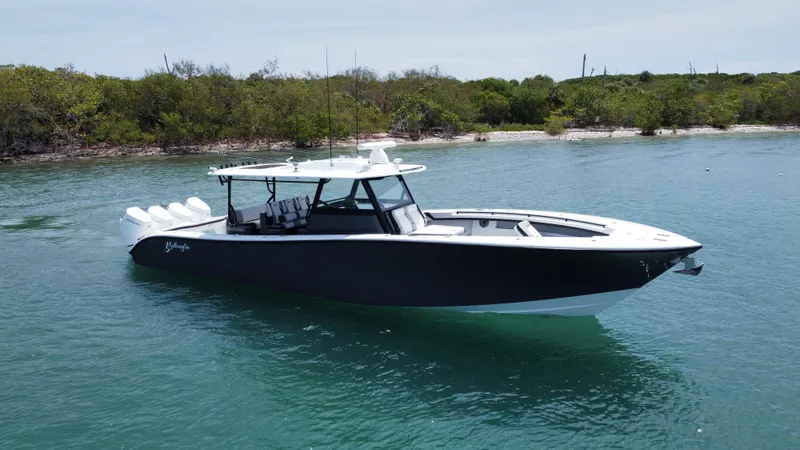 Slide: The Image of 2023 Yellowfin 42 boat on calm water near a lush shoreline. - 12