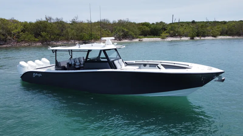 Slide: The Image of 2023 Yellowfin 42 boat on calm water near a lush shoreline. - 13