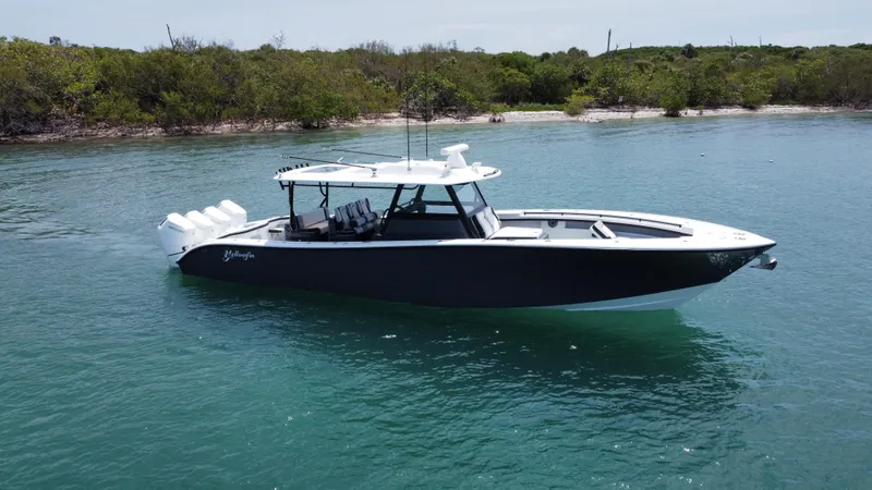 Slide: The Image of 2023 Yellowfin 42 boat on calm water near a lush shoreline. - 14